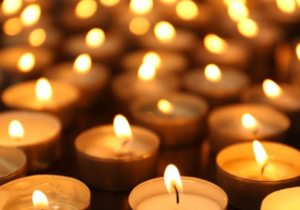 A close-up of many lit tealight candles creating a warm, glowing atmosphere.