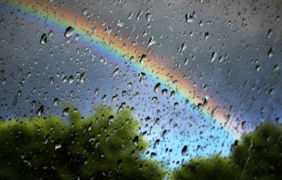 A rainbow viewed through a rainy window pane
