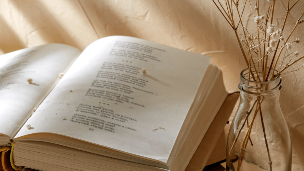 Open book of poetry next to a glass jar of flowers