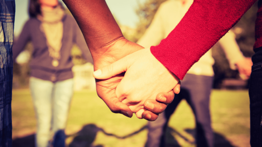 Close-up of two people of different races holding hands