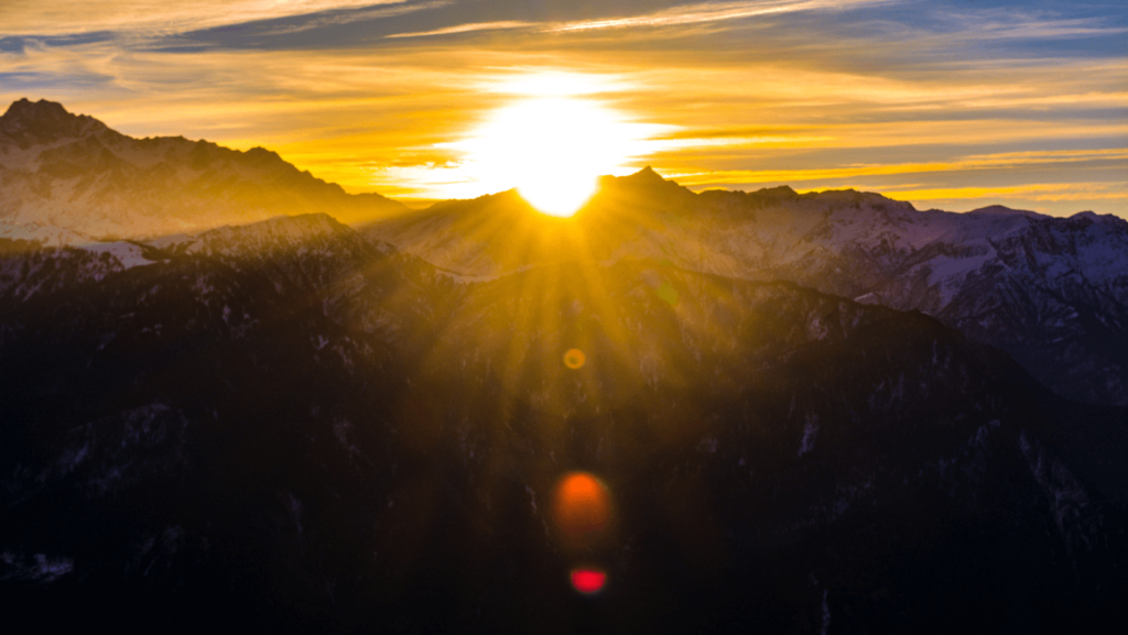 The sun rising over a mountain silhouetted against the sky