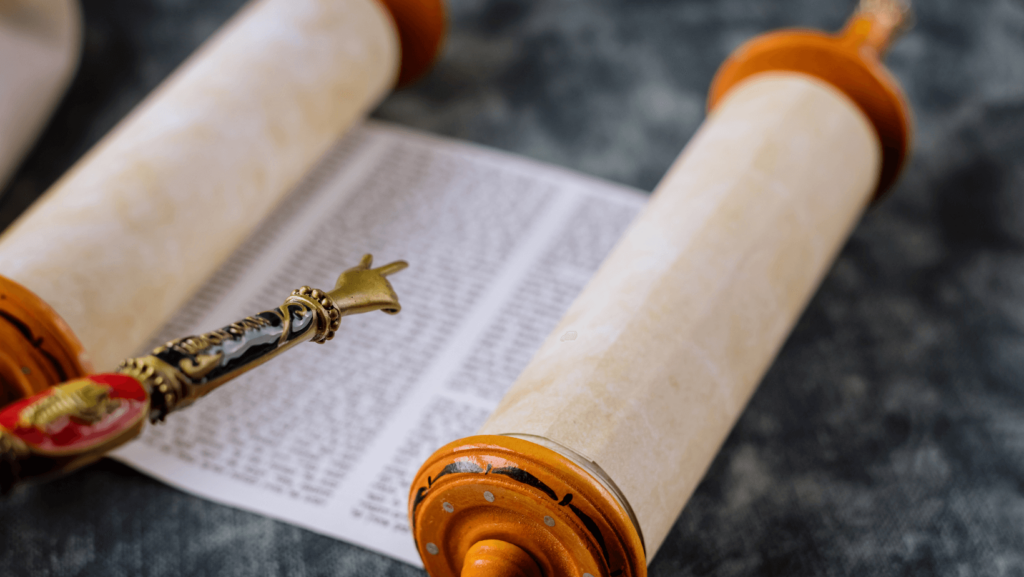 An open Torah scroll with a yad pointing to it