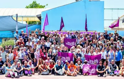 A large group of people posing together outdoors, holding purple flags and banners.