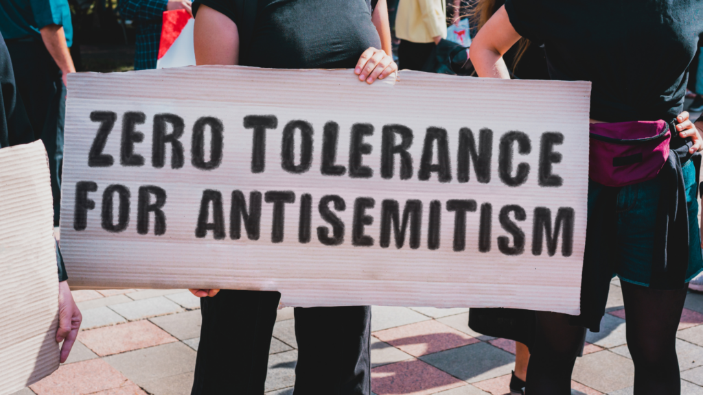 Person holding a sign reading Zero Tolerance for Antisemitism during a protest.