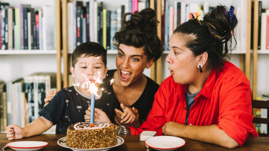 Two women with a child who is blowing out a birthday candle.