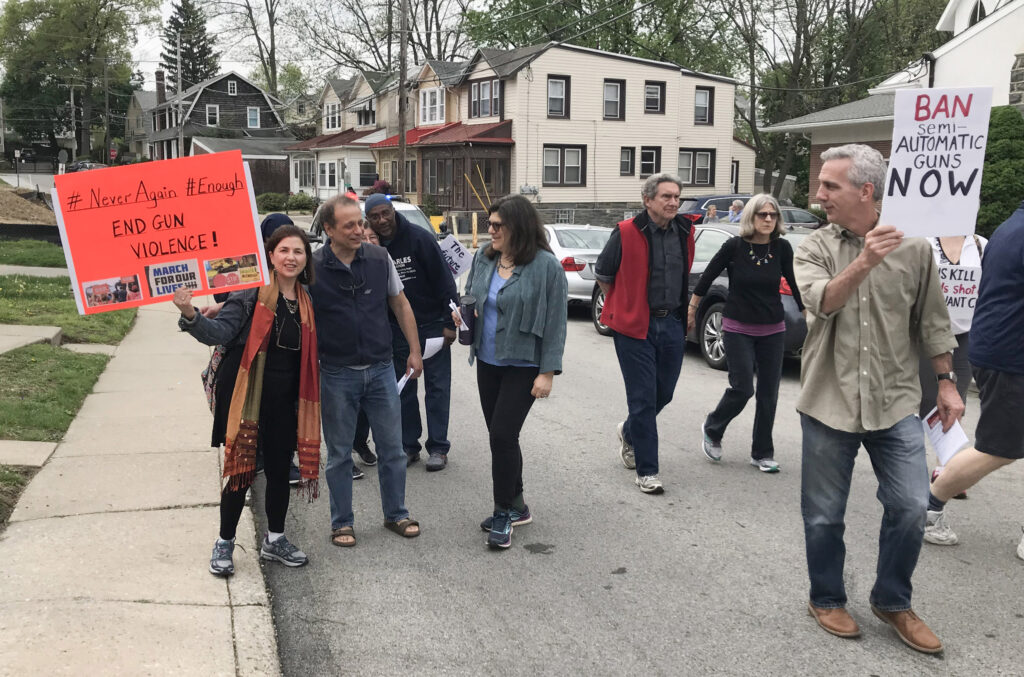 Members of Or Zarua demonstrate in the street against gun violence, holding signs like "Ban Automatic Weapons Now."