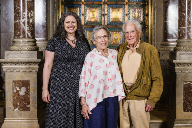 Standing in front of a synagogue ark at RRC's 2023 graduation: Rabbi Rachel Weiss with JRC congregants Sallie Gratch and Alan Gratch.