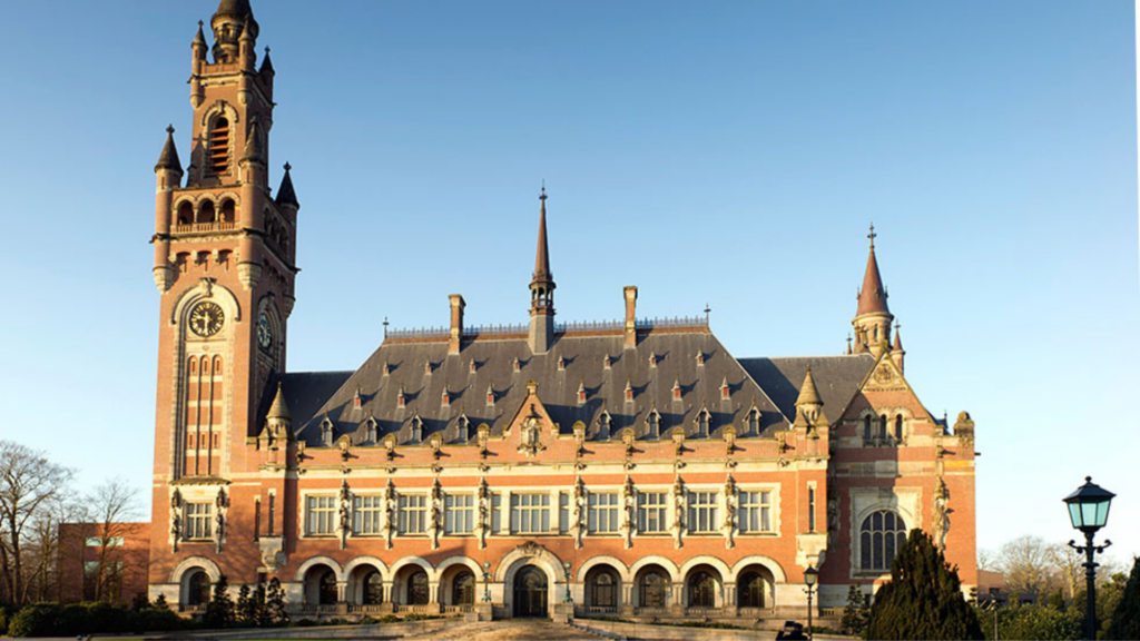 A large, historic building with a tall clock tower and spires, set against a clear blue sky.