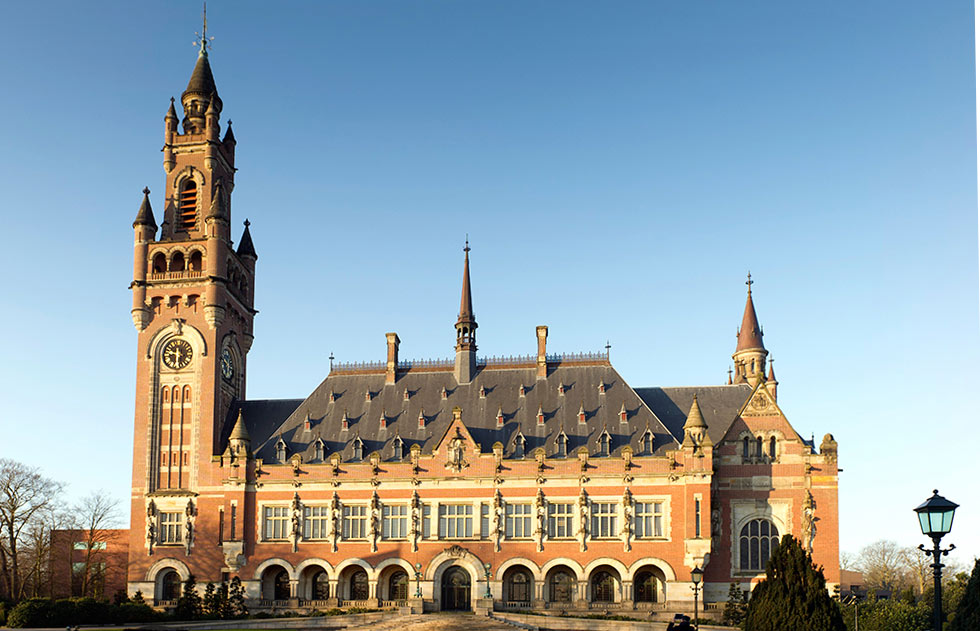 A grand, historic building with a tall clock tower against a clear blue sky.
