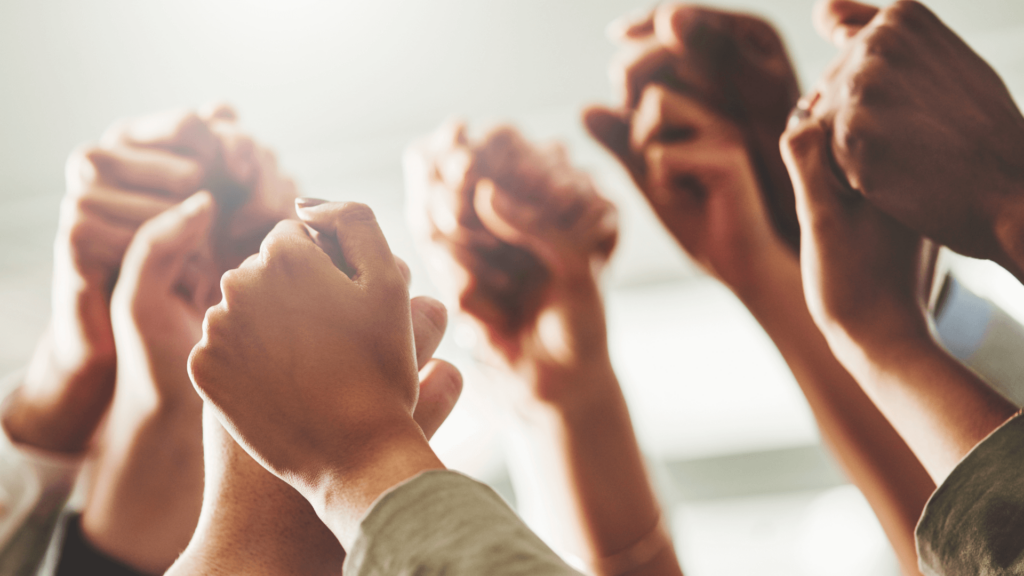 Close up of a group of raised clasped hands