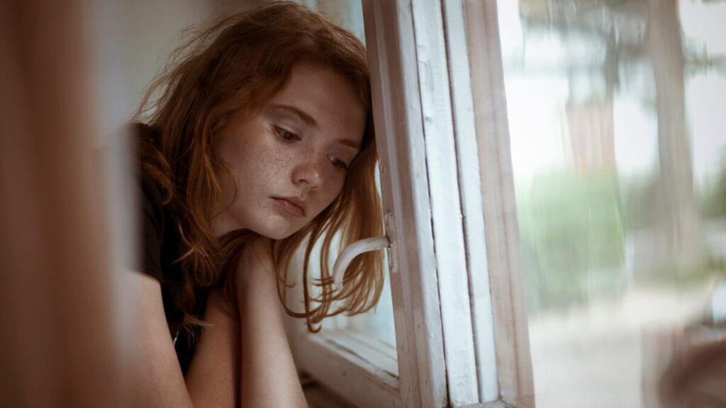 lonely young women leaning her head against a window