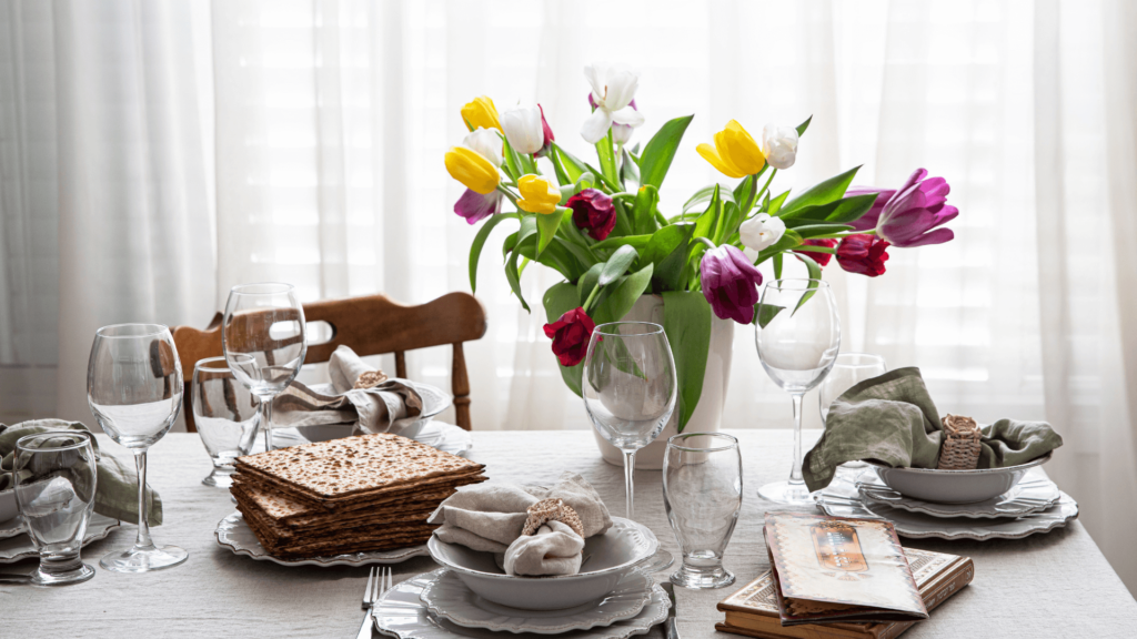 Seder table with matzah, prayer books, table settings, and a vase of tulips