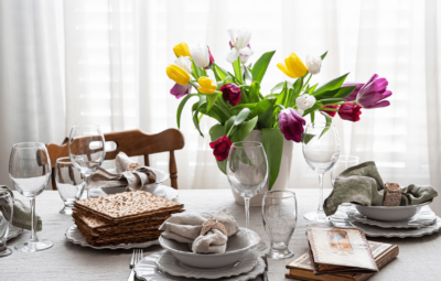 Seder table with matzah, prayer books, table settings, and a vase of tulips