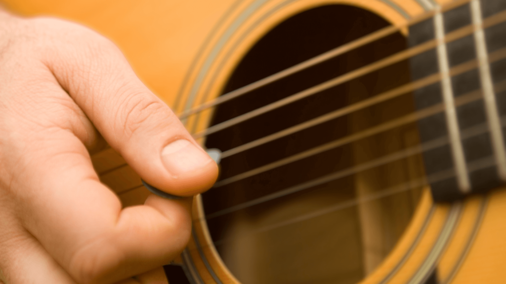 A close-up of a person's hand strumming an acoustic guitar
