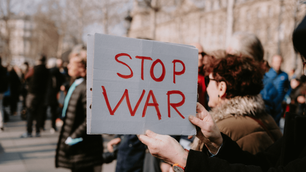 A person at a protest holding a sign that says "Stop War"