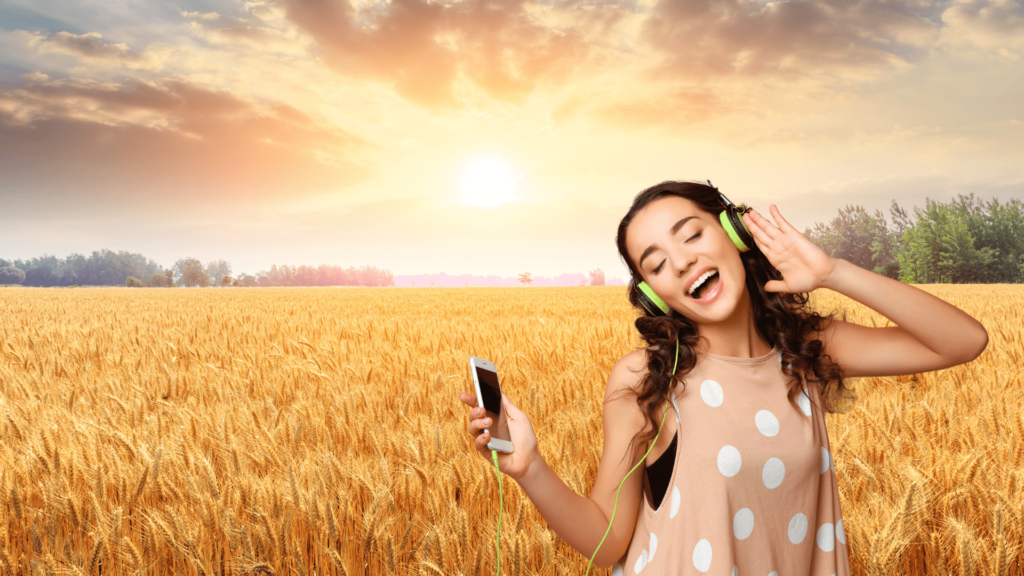 A woman wearing headphones and singing to music on her phone superimposed over a wheat field