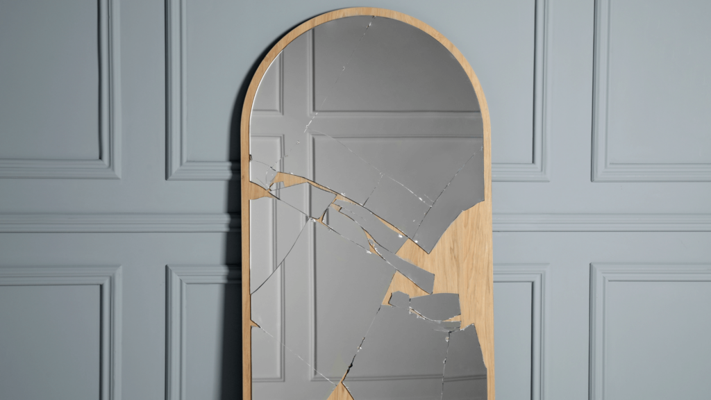 A broken mirror standing against a gray wall