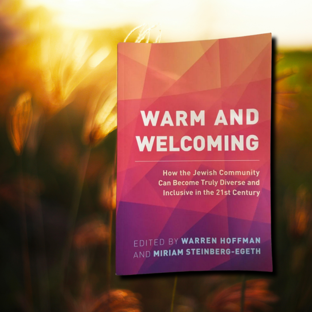 Book titled Warm and Welcoming with a blurred grassy background.