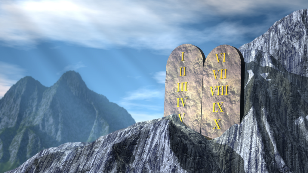 Stone tablets with Roman numerals on a mountain under a blue sky.