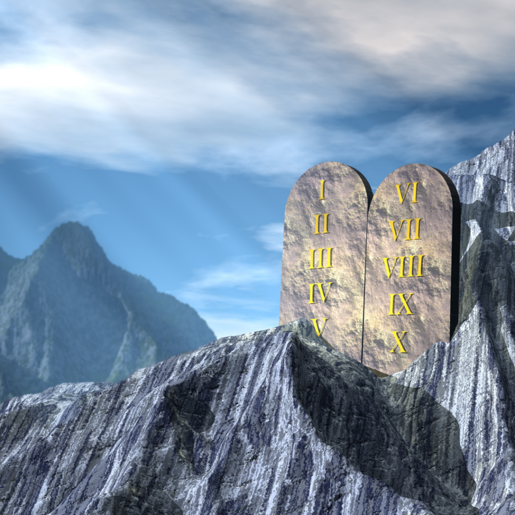 Stone tablets with Roman numerals on a rocky mountain backdrop under a blue sky.