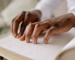 Hands reading a Braille book.