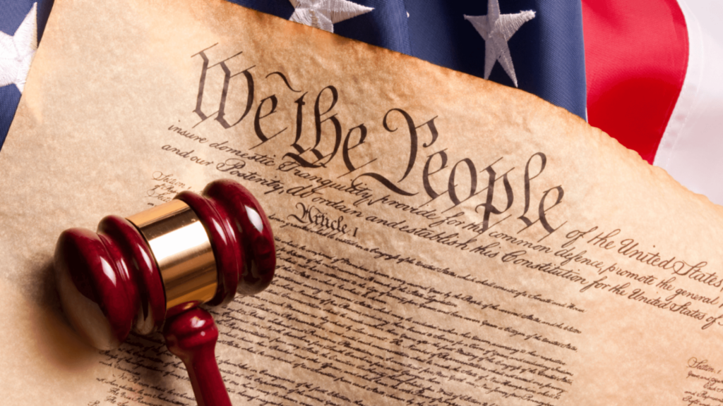 The Declaration of Independence with a gavel in the foreground and an American Flag behind it