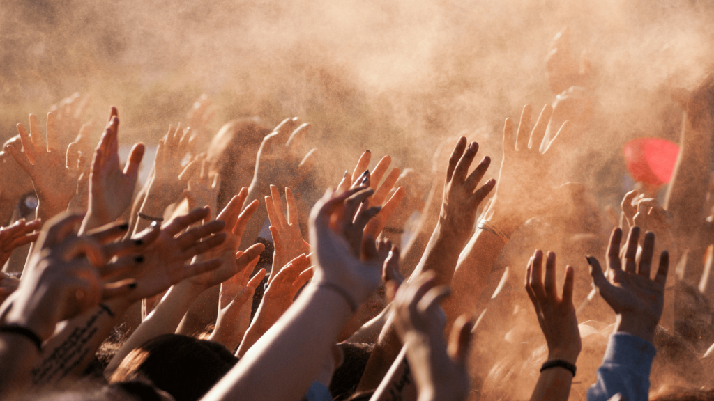 A group of people's hands raised against a tan background