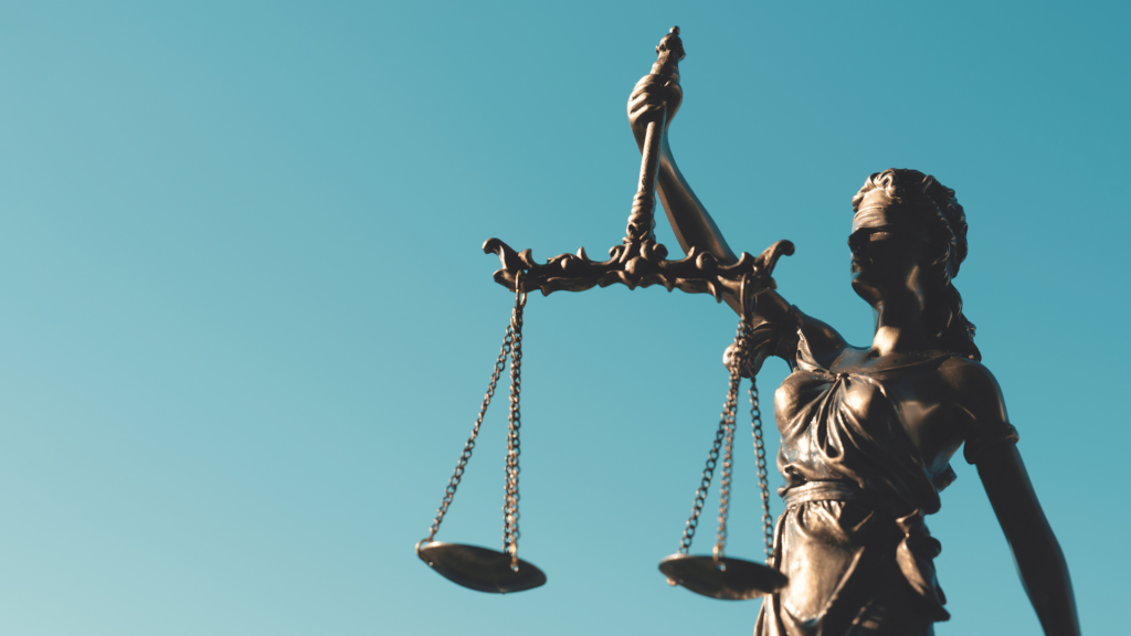 Statue of Lady Justice holding scales against a clear blue sky.