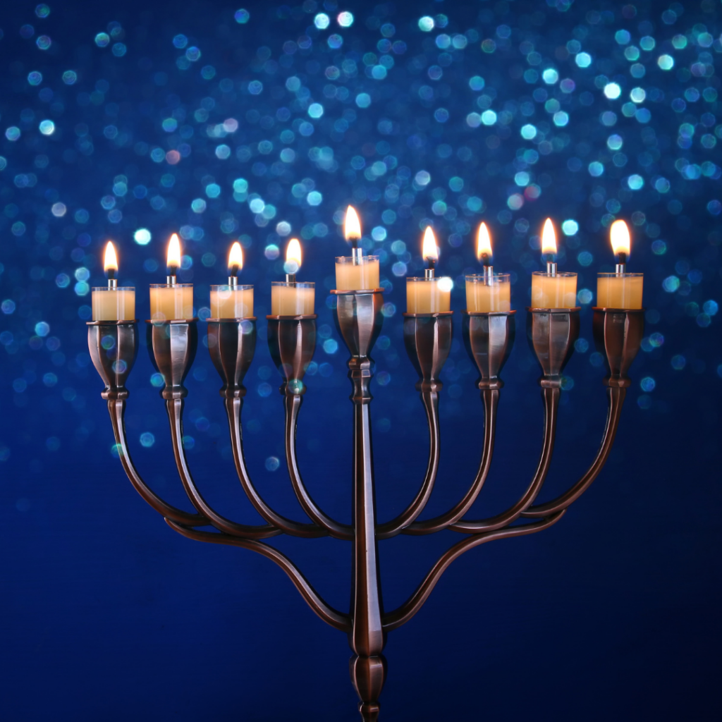 A menorah with nine lit candles against a sparkling blue background.