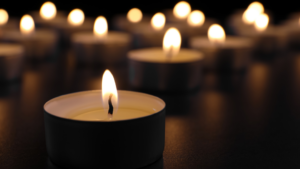 Lit tealight candles arranged on a reflective surface in a dimly lit setting.