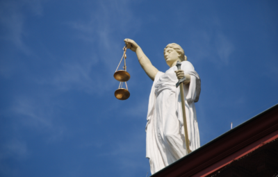 Statue of Lady Justice holding scales against a blue sky background.