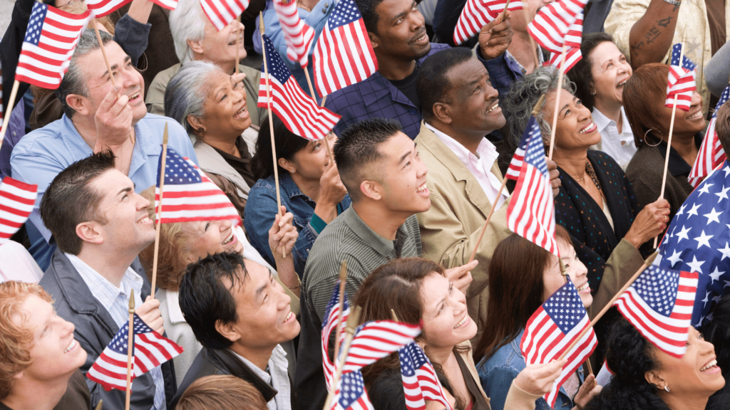 A multicultural group of people holding small American flags