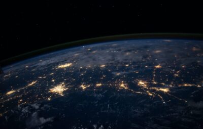 View of Earth from space at night, showing city lights illuminating the darkened surface.