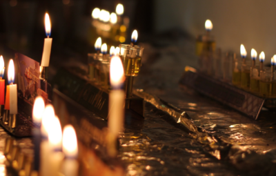 Lit menorahs with candles glowing in a dim setting, symbolizing the celebration of Hanukkah.