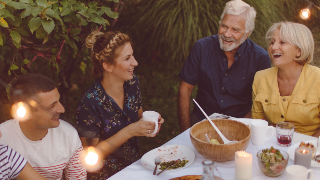 A younger couple and older couple eating outside with a tree behind them