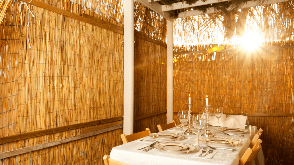 A dining table set with place settings inside a sukkah