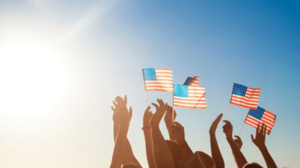 Small American flags being waved against a blue sky