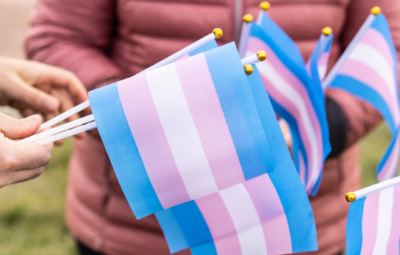 People holding small transgender flags outdoors.