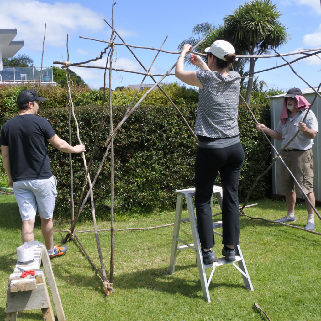 three people building a sukkah together