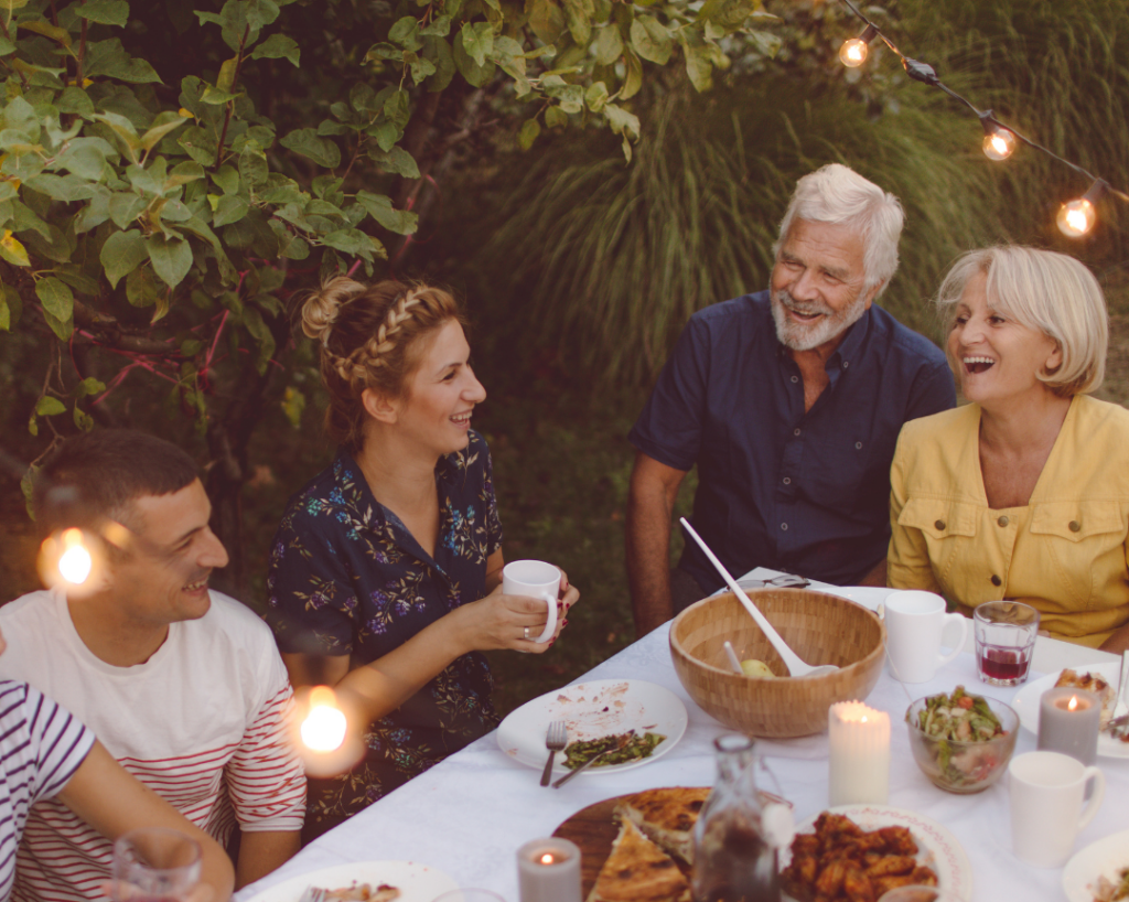 People talking and laughing together over dinner outside.