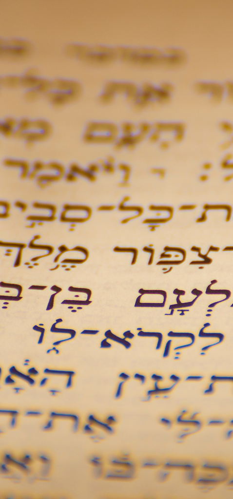Close-up of Hebrew script on aged paper with selective focus, showing handwritten characters in dark ink.