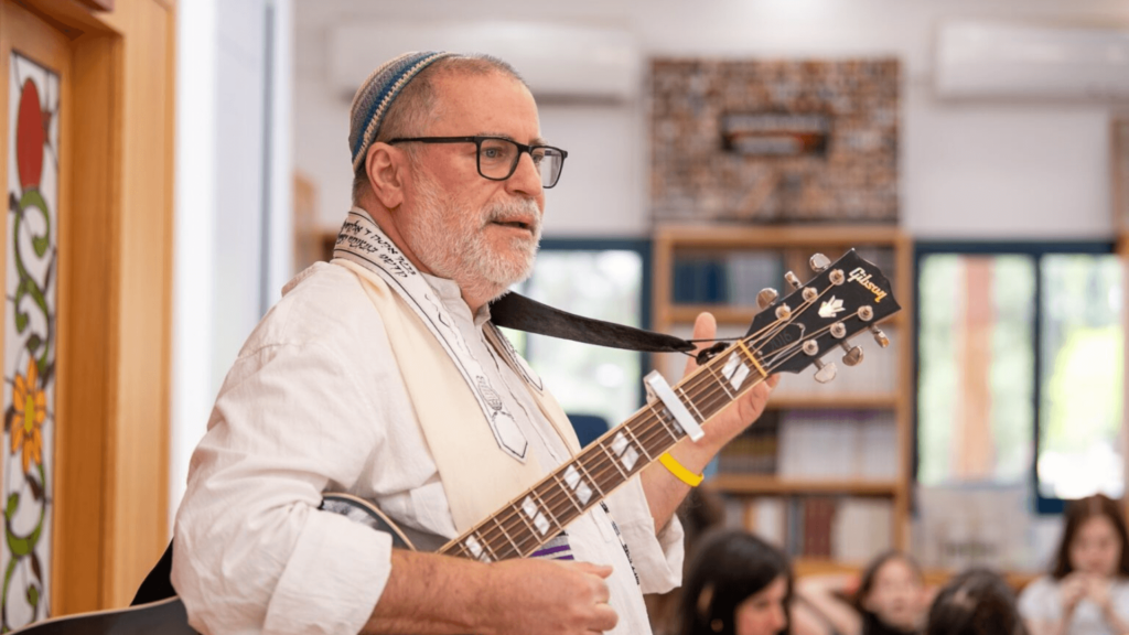 Rabbi Steve Burnstein with an acoustic guitar in front of a congregation