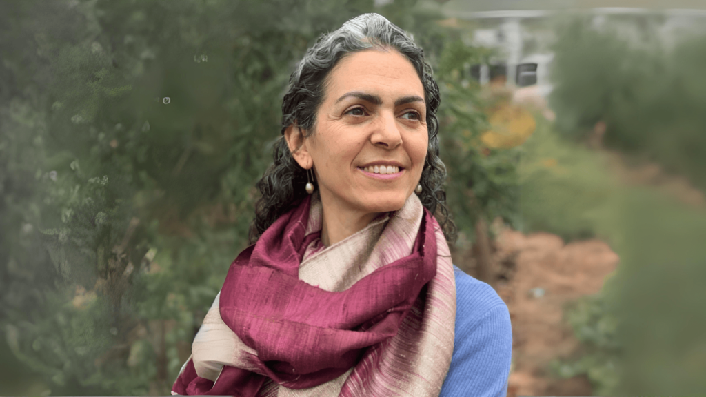 Daria Jacobs-Velde, a white woman with gray curly hair and wearing a maroon scarf