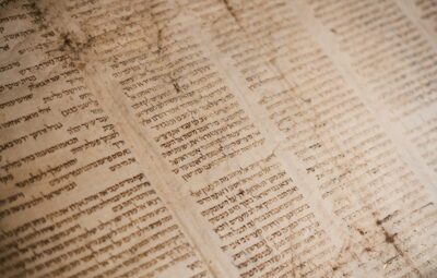 A close-up of an ancient Hebrew manuscript with aged, sepia-toned paper and visible signs of wear.
