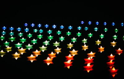 Colorful origami boats arranged in rows against a black background, forming a gradient from blue to red.