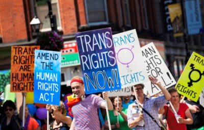 A group of people at a pride parade holding signs advocating for transgender rights.