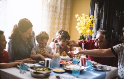 Family enjoying a meal together, with smiles and laughter around a table set with food and drinks.