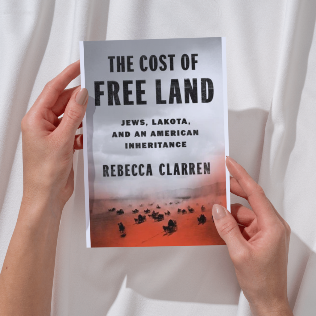 Person holding a book titled The Cost of Free Land by Rebecca Clarren.