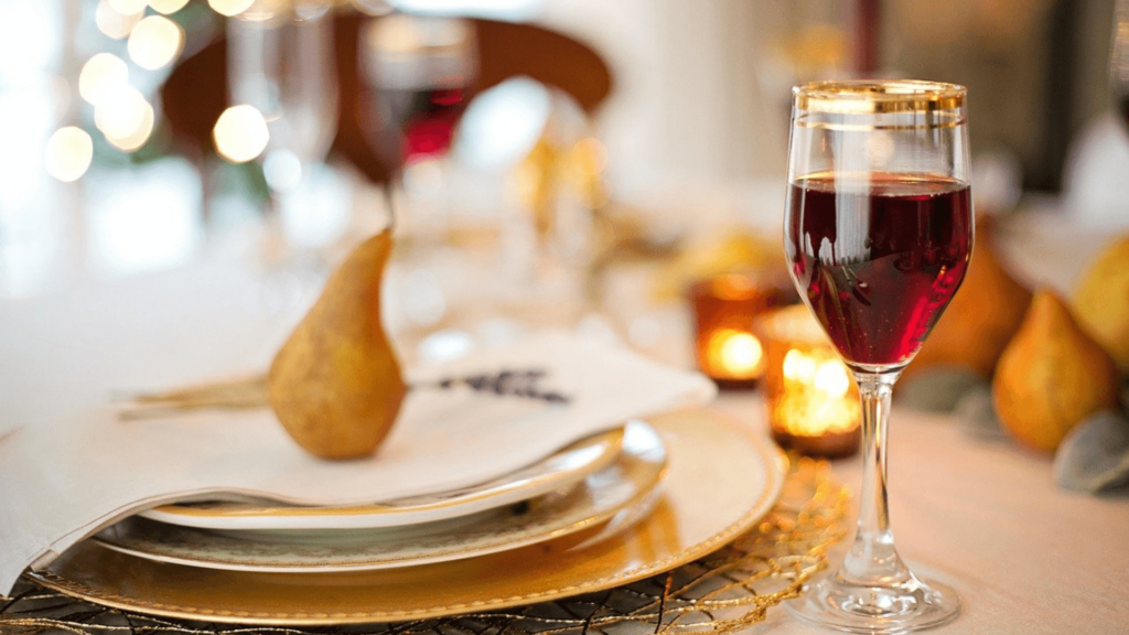 A Thanksgiving place setting with multiple plates, a glass of wine, and a napkin