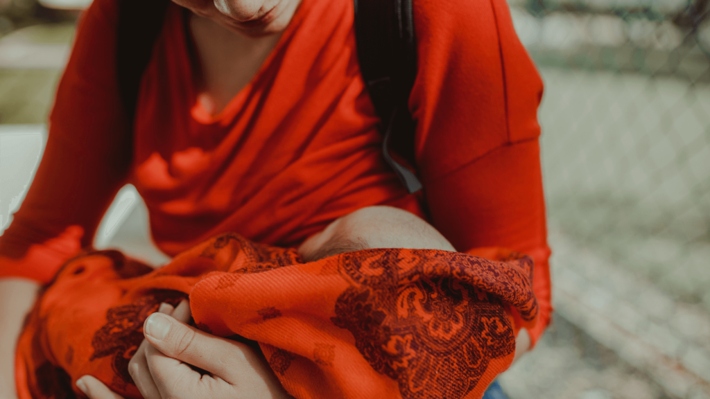 Close-up of a woman in a red dress holding a baby